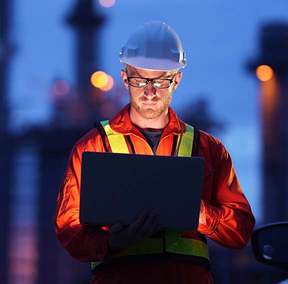 Engineer using laptop working while standing over natural gas power plant